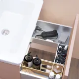 Stijlvolle badkamer inspiratie met beige wastafelmeubel met binnenlade, bovenkast, open plank, ovale spiegel met verlichting, bijpassende hanglampen, plank onder de spiegel en wandgemonteerd toilet. Wanden met lichte, langwerpige tegels