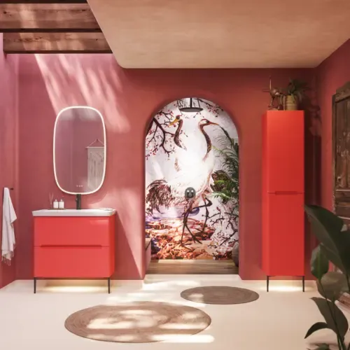 Badkamerinspiratie met rode muren, zacht gevormde rode wastafelmeubel en hoge kast, elegante witte wastafel en een prachtige ovale spiegel met licht die samen met de natuurlijke omgeving een vintage uitstraling creëren