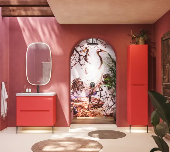 Badkamerinspiratie met rode muren, zacht gevormde rode wastafelmeubel en hoge kast, elegante witte wastafel en een prachtige ovale spiegel met licht die samen met de natuurlijke omgeving een vintage uitstraling creëren