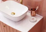 Grote vintage badkamer met terracottakleurig wastafelmeubel, opzetwastafel, ovaal spiegel met messingrand, roze en grijze tegels voor een romantische, vrouwelijke uitstraling