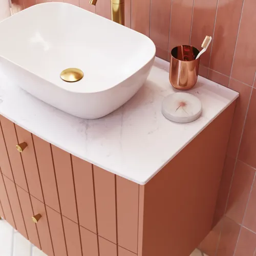 Grote vintage badkamer met terracottakleurig wastafelmeubel, opzetwastafel, ovaal spiegel met messingrand, roze en grijze tegels voor een romantische, vrouwelijke uitstraling
