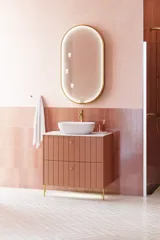 Grote vintage badkamer met terracottakleurig wastafelmeubel, opzetwastafel, ovaal spiegel met messingrand, roze en grijze tegels voor een romantische, vrouwelijke uitstraling