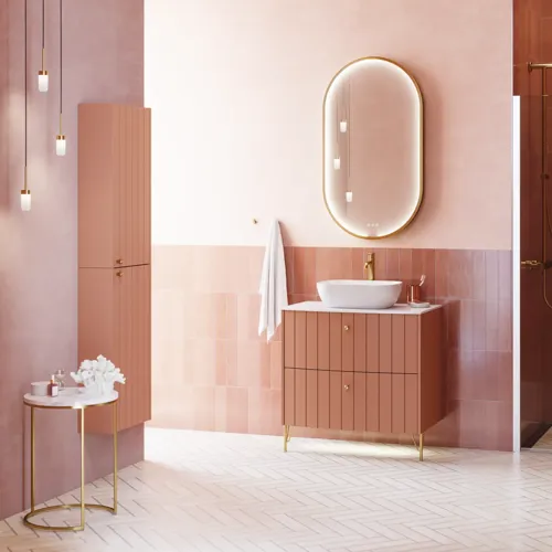Grote vintage badkamer met terracottakleurig wastafelmeubel, opzetwastafel, ovaal spiegel met messingrand, roze en grijze tegels voor een romantische, vrouwelijke uitstraling