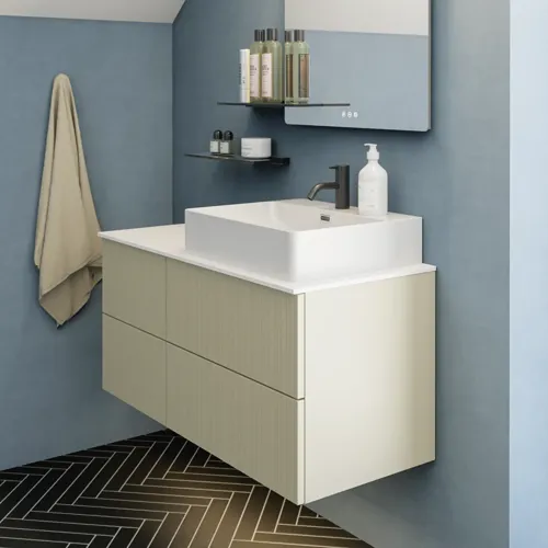 Badkamer met schuin plafond, beige meubels met groeven, elegante werkblad en vierkante wastafel, mooie spiegel met planken, blauwe muren, grote ramen en zwarte visgraatvloer geven een lichte, stedelijke uitstraling.