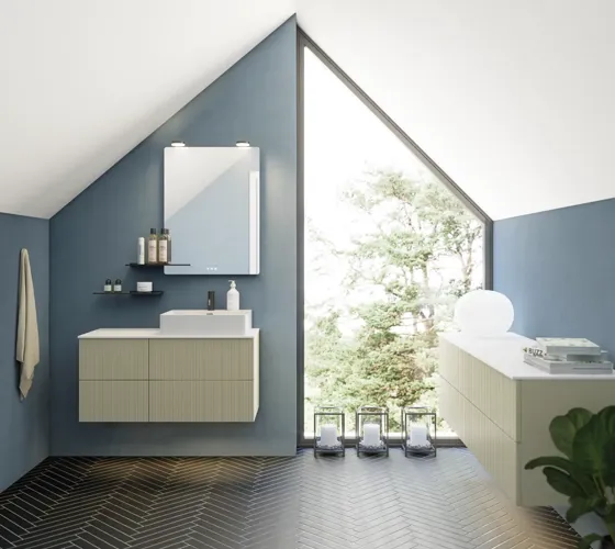 Badkamer met schuin plafond, beige meubels met groeven, elegante werkblad en vierkante wastafel, mooie spiegel met planken, blauwe muren, grote ramen en zwarte visgraatvloer geven een lichte, stedelijke uitstraling.
