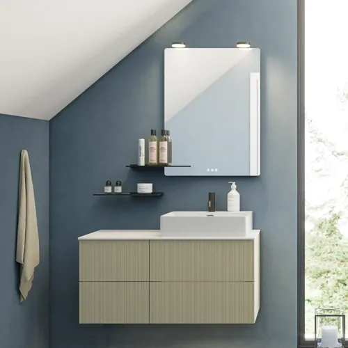 Badkamer met schuin plafond, beige meubels met groeven, elegante werkblad en vierkante wastafel, mooie spiegel met planken, blauwe muren, grote ramen en zwarte visgraatvloer geven een lichte, stedelijke uitstraling.