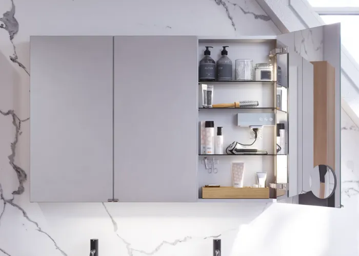 Badkamerinspiratie met wastafelkasten en bovenkasten in licht eikenhout met groeven, elegante dubbele wastafel, mooie spiegelkast met verlichting, visgraatvloer in licht hout en witte marmeren muur geven een klassieke, lichte en strakke uitstraling.