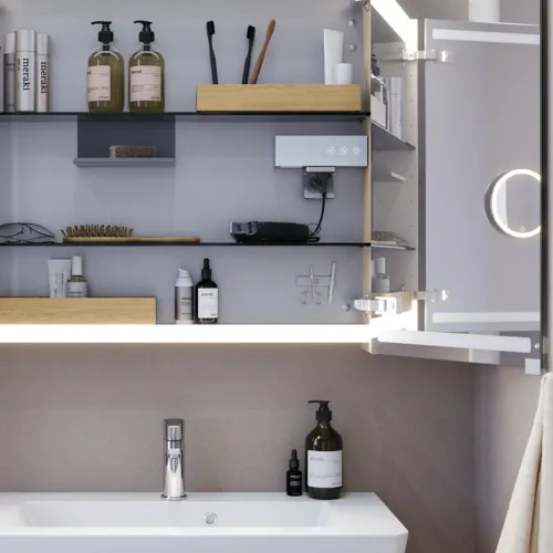 Kleine badkamerinspiratie met wastafelkast en kast boven het toilet in beige speciale kleur, elegante spiegelkast met geïntegreerde verlichting, de lichte kleuren en het witte gordijn creëren een romantische en vrouwelijke sfeer.