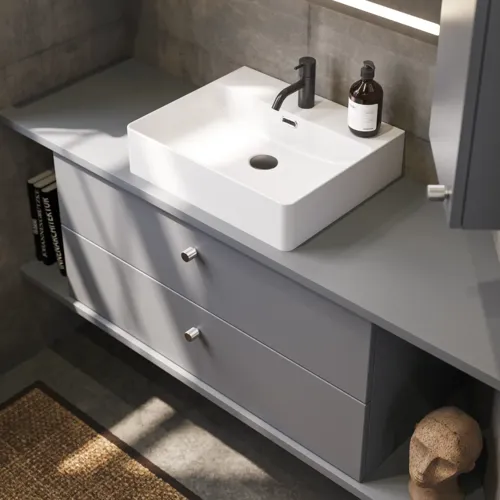 Badkamer met schuine muren inspiratie, grijze wastafelmeubel en bovenkast, op maat gemaakte aanrechtbladen, moderne vierkante opzetwastafel, vierkante spiegel met verlichting, ruwe betonnen muren en vloeren geven een stedelijke uitstraling