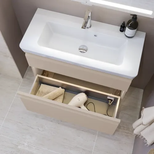 Kleine badkamerinspiratie met wastafelkast en kast boven het toilet in beige speciale kleur, elegante spiegelkast met geïntegreerde verlichting, de lichte kleuren en het witte gordijn creëren een romantische en vrouwelijke sfeer.