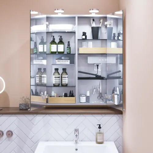Kleine badkamerinspiratie met wastafelkastje in speciale kleur met geïntegreerde greep, spiegelkast met lampen, decoratieve spiegels met getinte glazenschap, witte visgraattegels geven een strakke en klassieke uitstraling.