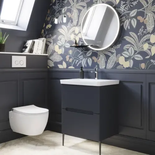 Badkamerinspiratie met donkerblauwe wandpanelen, romantisch bloemenbehang, donkerblauw wastafelmeubel met zachte vormen en een prachtige ronde spiegel met licht dat een vintage uitstraling creëert