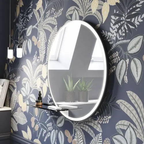 Badkamerinspiratie met donkerblauwe wandpanelen, romantisch bloemenbehang, donkerblauw wastafelmeubel met zachte vormen en een prachtige ronde spiegel met licht dat een vintage uitstraling creëert