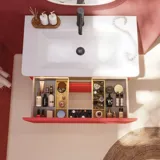 Badkamerinspiratie met rode muren, zacht gevormde rode wastafelmeubel en hoge kast, elegante witte wastafel en een prachtige ovale spiegel met licht die samen met de natuurlijke omgeving een vintage uitstraling creëren