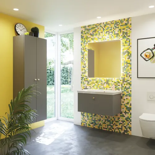 Badkamerinspiratie met badkamermeubels in mat grijs met elegante wastafel, mooie vierkante spiegel, grijze vloer en kleine tegels in verschillende tinten geel en groen, die met de gele muur een heldere en speelse uitdrukking geven.
