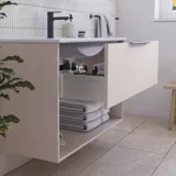 Badkamerinspiratie met roze badmeubel met elegante groeven en mooie wastafel, witte tegels op de muren en grote beige tegels op de vloer creëren een romantische en vrouwelijke look.