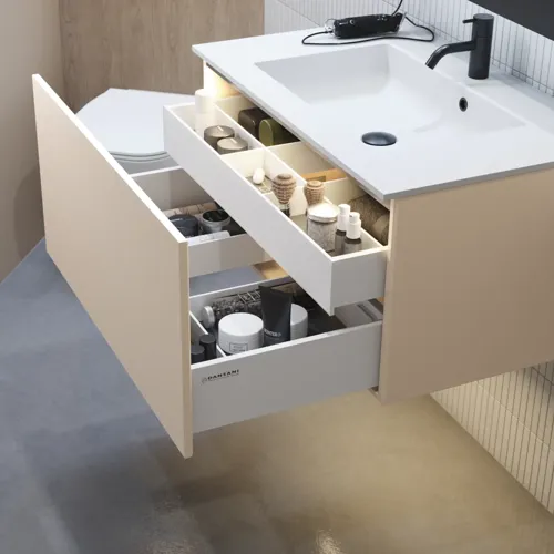 Stijlvolle badkamer inspiratie met beige wastafelmeubel met binnenlade, bovenkast, open plank, ovale spiegel met verlichting, bijpassende hanglampen, plank onder de spiegel en wandgemonteerd toilet. Wanden met lichte, langwerpige tegels