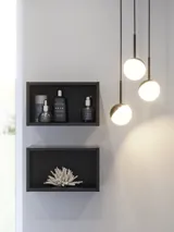 Badkamerinspiratie met stijlvolle badkameraccessoires, elegante ronde hanglampen en minimalistische zwarte open modules die de badkamer compleet maken.