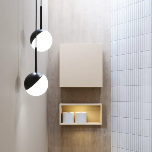 Stijlvolle badkamer inspiratie met beige wastafelmeubel met binnenlade, bovenkast, open plank, ovale spiegel met verlichting, bijpassende hanglampen, plank onder de spiegel en wandgemonteerd toilet. Wanden met lichte, langwerpige tegels