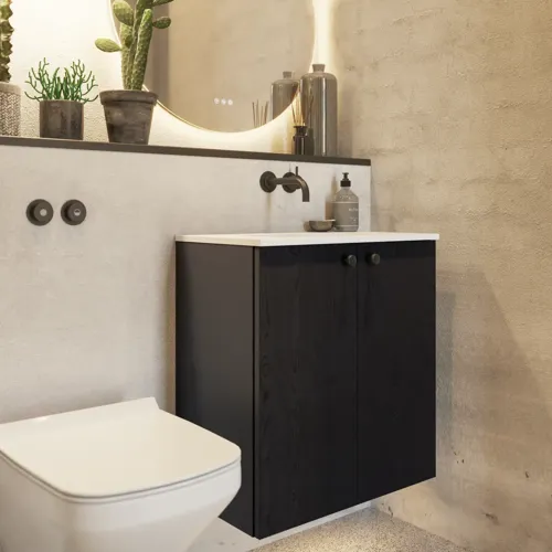 Badkamerinspiratie met een wastafelkast in zwart eikenhout, een elegante ronde spiegel en wastafel, stijlvolle accessoires, cactusplanten en muren van ruwe materialen geven een ruw, industrieel en urban uiterlijk.