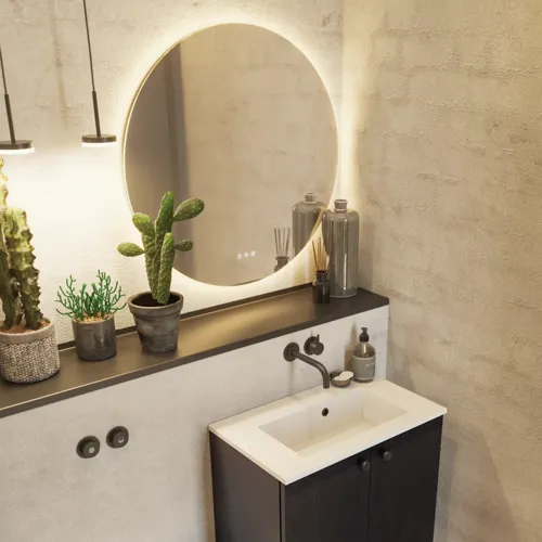 Badkamerinspiratie met een wastafelkast in zwart eikenhout, een elegante ronde spiegel en wastafel, stijlvolle accessoires, cactusplanten en muren van ruwe materialen geven een ruw, industrieel en urban uiterlijk.