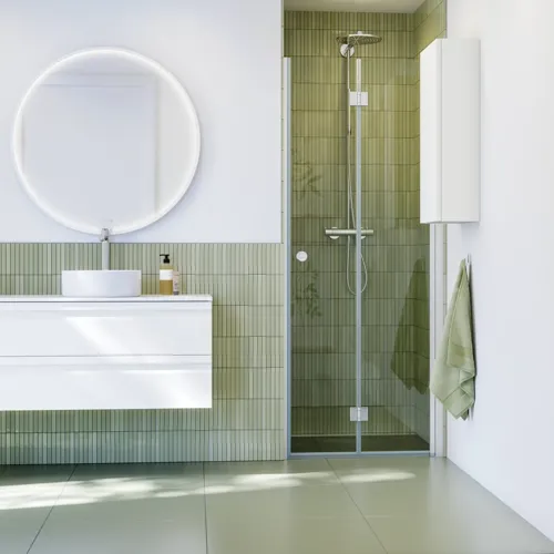 Badkamerinspiratie met wit badkamermeubel, elegante ronde spiegel en douchenis met vouwdeur in helder glas en profielen in satijn, groene langwerpige tegels geven een verfijnde uitstraling.