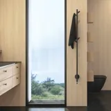 Stijlvolle badkamer in Scandinavische en Japandi stijl met lichte houten muren, ronde spiegel en minimalistische badkamermeubels.