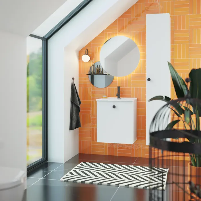 Badkamer met schuin plafond inspiratie met klein wit badmeubel en hoge kast met ronde zwarte handgrepen, evenals mooie ronde spiegel, oranje tegels geven een frisse en moderne look.