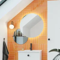 Badkamer met schuin plafond inspiratie met klein wit badmeubel en hoge kast met ronde zwarte handgrepen, evenals mooie ronde spiegel, oranje tegels geven een frisse en moderne look.