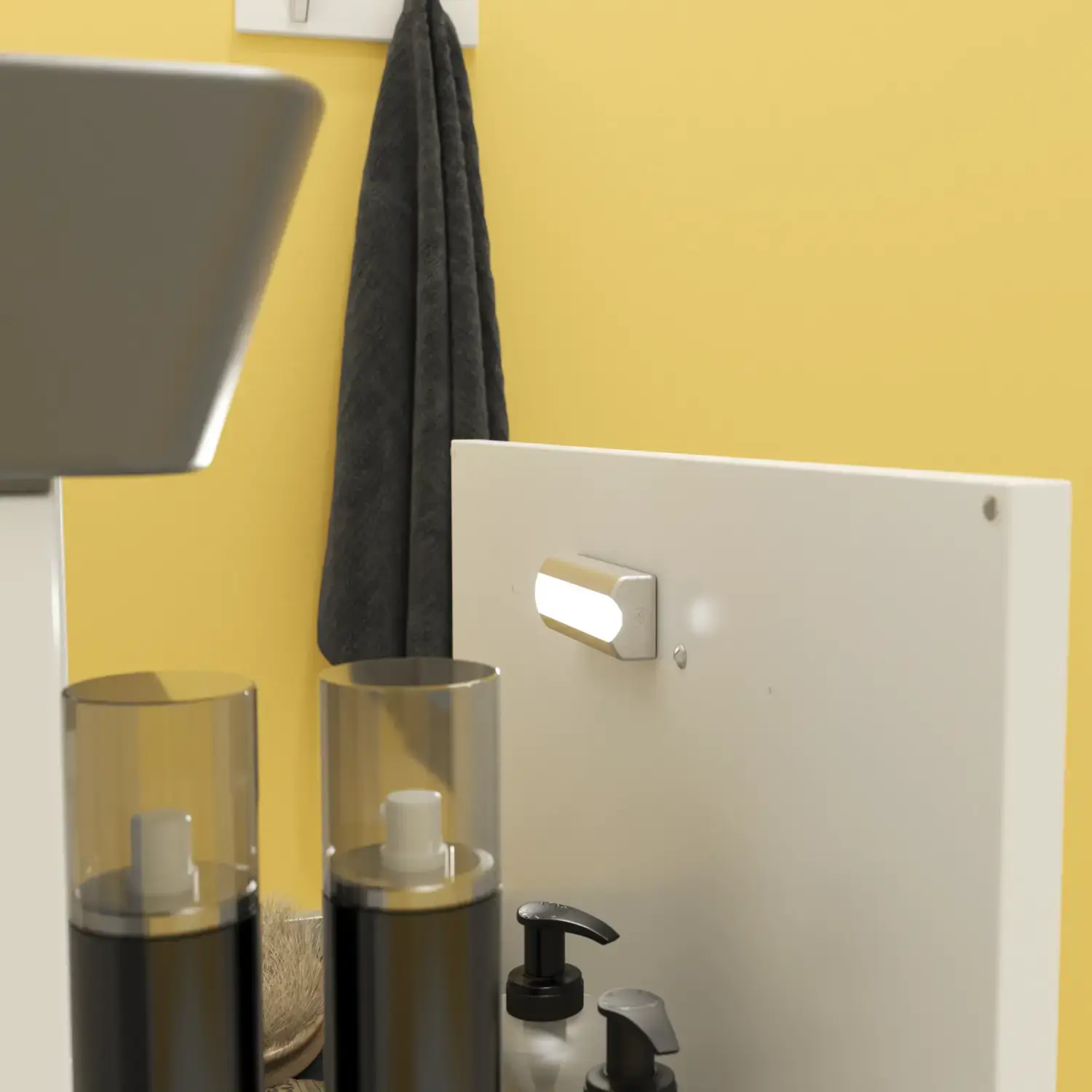 Kleine badkamerinspiratie met een wit wastafelkastje met zwarte greep en zwarte elegante wastafel, mooie ronde spiegel met zwarte rand, verschoven wandkasten en een terrazzo wand en vloer en gele muren geven een gedurfde en moderne uitstraling.