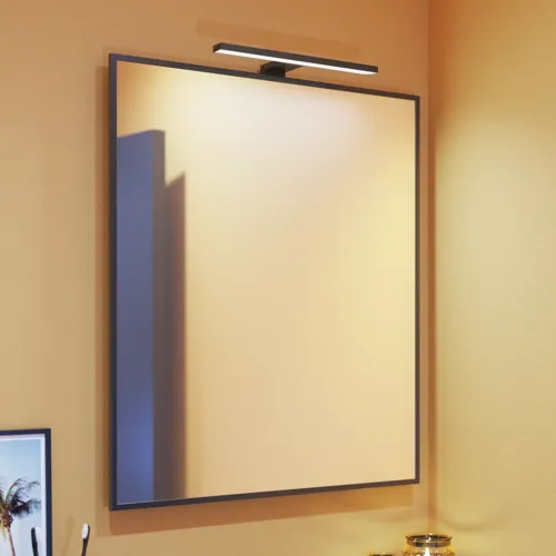 Kleine badkamerinspiratie met schuine, warme gele muren en een minimalistische vierkante spiegel met een strakke zwarte rand, samen met een elegante spiegelverlichting die een vleugje elegantie aan je badkamer toevoegt.