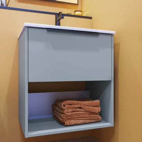 Kleine badkamerinspiratie met schuine en warme gele muren, elegant lichtblauw wastafelmeubel met open ruimte die een unieke sfeer creëert, en een dunne, strakke wastafel die zowel functionaliteit als elegantie aan je badkamer toevoegt.