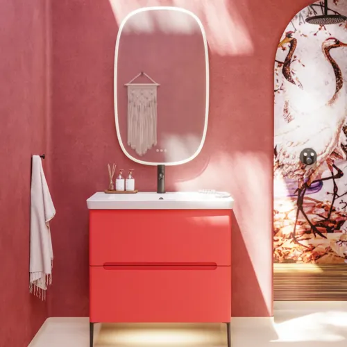 Badkamerinspiratie met rode muren, zacht gevormde rode wastafelmeubel en hoge kast, elegante witte wastafel en een prachtige ovale spiegel met licht die samen met de natuurlijke omgeving een vintage uitstraling creëren