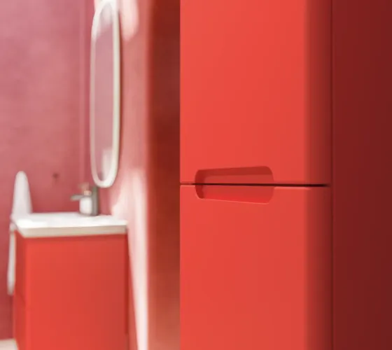 Badkamerinspiratie met rode muren, zacht gevormde rode wastafelmeubel en hoge kast, elegante witte wastafel en een prachtige ovale spiegel met licht die samen met de natuurlijke omgeving een vintage uitstraling creëren